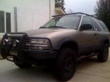 westin brush guard with KC daylighters. the bottom 8 inches of the brush guard was cut off and removed for more clearance then the mounts were reworked and welded to the frame higher than before. lower valance was removed. custom rock sliders built and installed and a custom top roof rack is in progress of being built. spray on bed liner on fender flares and lower 12 inches of body. stock rims painted black. black out lower turn signal lights.