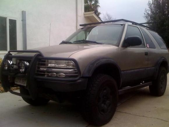 westin brush guard with KC daylighters. the bottom 8 inches of the brush guard was cut off and removed for more clearance then the mounts were reworked and welded to the frame higher than before. lower valance was removed. custom rock sliders built and installed and a custom top roof rack is in progress of being built. spray on bed liner on fender flares and lower 12 inches of body. stock rims painted black. black out lower turn signal lights.