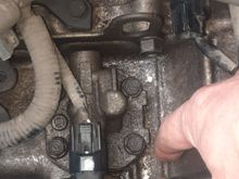 Not sure what this plate/ part is, connected by 4 bolts with a sensor attached but could the gasket be the cause. It sits under the air filter assembly on the top of the casing.
I could try retightening the 4 bolts, if anyone knows what torque setting to use?  I am pointing to where the oil pools.