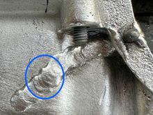 The upper circle shows what might be a crack in the weld. The lower circle shows scabbing. This might be minor or covering something major. I would take a pick and poke at the area. More than likely material will flake off. It is what is underneath you need to inspect. This could be nothing or a stress riser that could cause that boss to eventually fail. All depends on the stress level it sees. 