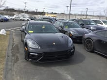 Front of black 2018 Panamera Turbo Sport Turismo; to its right (in this view) and slightly behind is the black 2018 Panamera 4 Sport Turismo