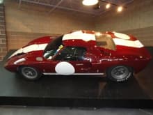 Ford GT-40 racecar in maroon with white racing stripes.