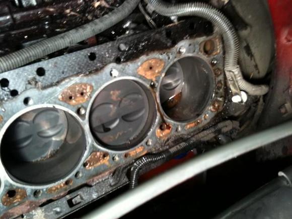 The coolant in the far right cylinder was from removing the head.  I'm most concerned with the orange "blob" on the middle cylinder...what is it?  Also, the oil on the very right edge of the head, is that from oil getting past the gasket somehow?