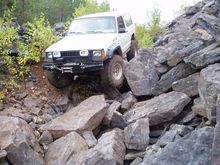 Front left tire is hanging by the sidewall a foot off the ground.