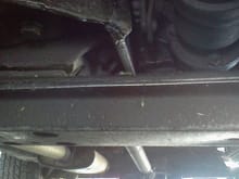 This picture show a rod (top center) welded to the cross member holding the transmission.