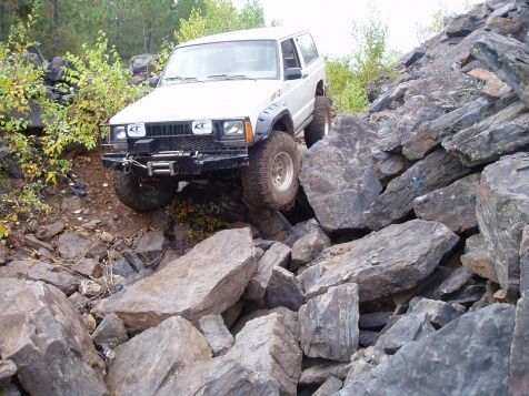 Front left tire is hanging by the sidewall a foot off the ground.
