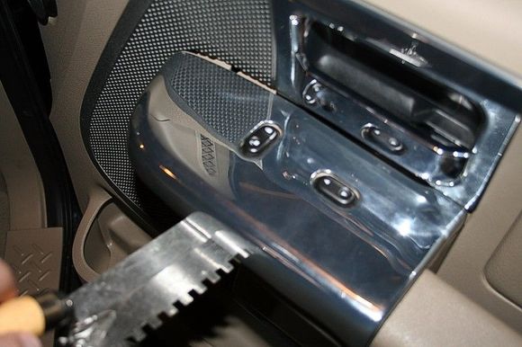 Step 1: Using a scraper or flat metal tool, gently pry up the passenger side door control panel.