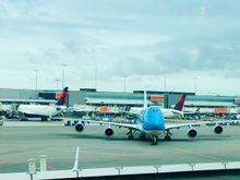 KLM 747 framed by Delta tails at Schiphol