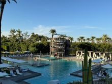 Pool area, water slide in distance, sandy area to the left of the slide.