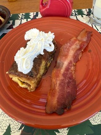 Eggnog French toast casserole w/ maple syrup and whipped cream (second slice). 