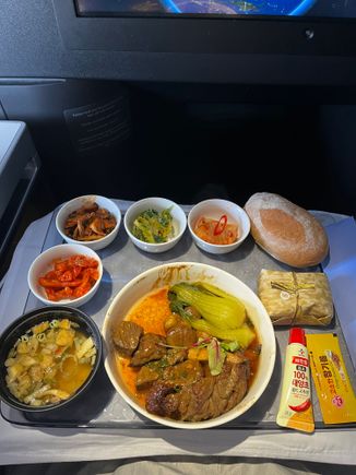 Korean Meal:
Top (left to right): Stir-fried spicy mushrooms, winter cabbage salad with ssamgjang, kimchi, dinner roll.
Middle: Dried sautéed squid with sweet chili 
Bottom: Soybean soup, Grilled beef, rice pack, gochujang and sesame oil packets. 