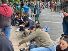 People sitting on the curb at Borough Market.  Any flat place is game for a dinner table.