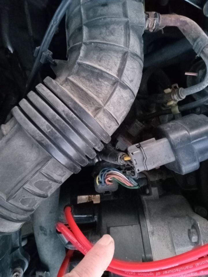 I'm not holding the connector in question, it is loose, down below that connector showing all the multi-colored wires. I'm holding the spark plug wires aside to show the area better.