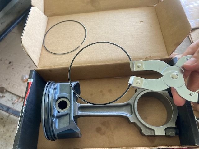 Installing the piston rings using a ring installer tool.  If you order the kit from Mizumo Auto, they clearly label the upper/middle/lower rings which makes it a breeze to install these.  Be sure to reference the Schwartz Service Manual for the 3.7L engine as well.  Place the rings all 90 degrees off from one another.  The ring material is steel nitrated.  