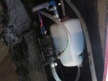 Washer bottle in wing cavity behind front LHS wheel. Care needed to site it so wing baffle goes back on.