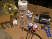 From left to right: New Four Seasons receiver/dryer bottle, A/C Flush tank with solvent, Four Seasons expansion valve, Suniso 5GS mineral oil, New and Old binary switches, valve core removal tool w/ cores, 100ml Syringe, 4 - 14oz cans of NOS Dupont Freon 12 refrigerant, Robinair R12 manifold gauges, Pittsburgh 2.5CFM vacuum pump, 3/16" to 1/4" high-side service port adapter, and Robinair R12/R-134a side can tap
