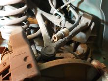 RH parkbrake sheath which cable runs through. Shown unclipped from the small Brembo parkbrake caliper. Snapped end fell off here so no cable visible in photo.