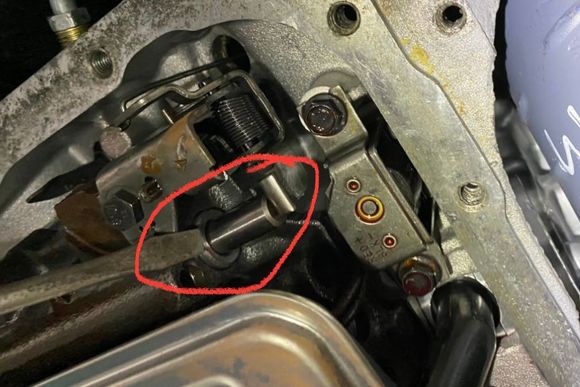 
This is the throttle valve (round shaft in red circle) , viewed with the transmission pan off. This is at the idle position, the lever is putting a small amount of pressure on the throttle valve and depressing it slightly.  At full throttle, the throttle valve is fully depressed and becomes invisible. 