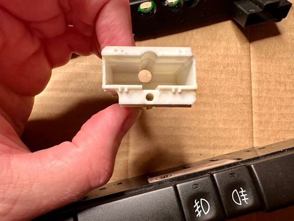 The bigger round hole is for the backlighting bulb, the smaller one is only used on the buttons that have an LED on indicator led like the seat heaters or Trac/ Off buttons