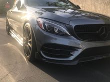 My lip is from RWCarbon. It goes over the center part of the stock lip (the left and right sides of the factor lip are removed). 

Also, the front bumper fins (whatever they are actually called) are similar to the bumper inserts you were asking about (the seller of mine also sells the ones you were looking at). I Installed them a few months ago and they appear to be holding up well. 