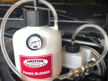 Motive bleeder connected to the fluid reservoir.  The plastic cover (engine paneling) needs to be removed.  Pull the large rubber hood steel off as the first step.