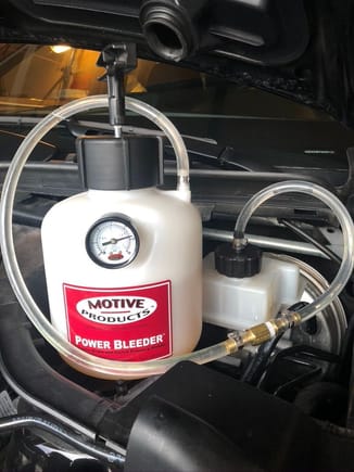 Motive bleeder connected to the fluid reservoir.  The plastic cover (engine paneling) needs to be removed.  Pull the large rubber hood steel off as the first step.