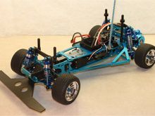 Highly-modified Kyosho Optima chassis re-engineered for onroad driving; narrowed F &amp; R track, custom bumper &amp; front shock tower, narrowed front CVDs, alloy F &amp; R arms, alloy Lazer carriers, belt-drive conversion, 3Racing Lazer shock set, Castle Sidewinder ESC &amp; Speedpassion 17.5T motor.