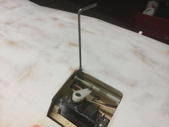 End of control rod in center of pic up against the release arm and rod coming up to top of wing