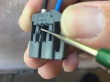 When you underneath the plastic as shown, the pin will come right out by pulling from the wire.