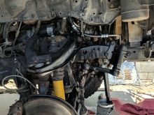 Jack with a bar that is pushing against steering pump to keep it nice and tight.